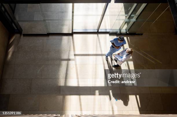 doctor talking to a nurse at the entrance hall of a hospital - healthcare and medicine from above stock pictures, royalty-free photos & images