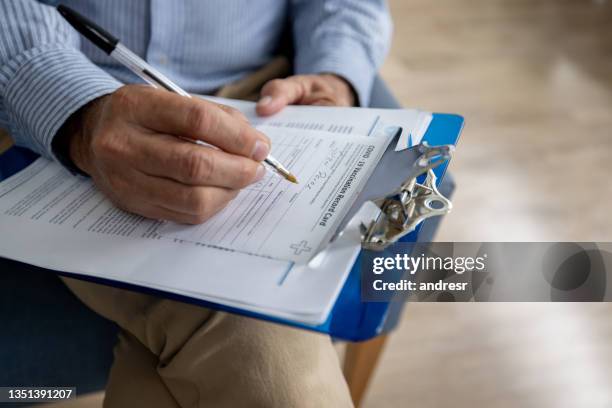 primer plano de un hombre que llena un formulario para vacunarse contra el covid-19 - registro fotografías e imágenes de stock