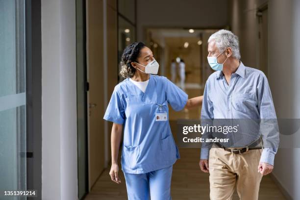 doctor talking to a patient in the corridor of a hospital while wearing face masks - male doctor man patient stockfoto's en -beelden