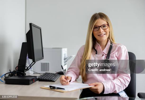 friendly doctor working at her office - practising stock pictures, royalty-free photos & images