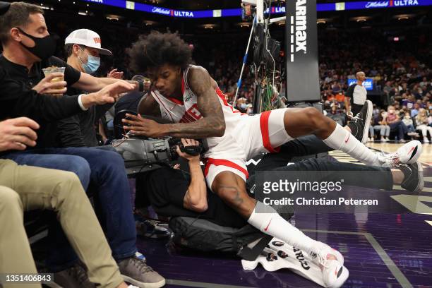 Kevin Porter Jr. #3 of the Houston Rockets falls onto a television camera-person during the first half of the NBA game against the Phoenix Suns at...