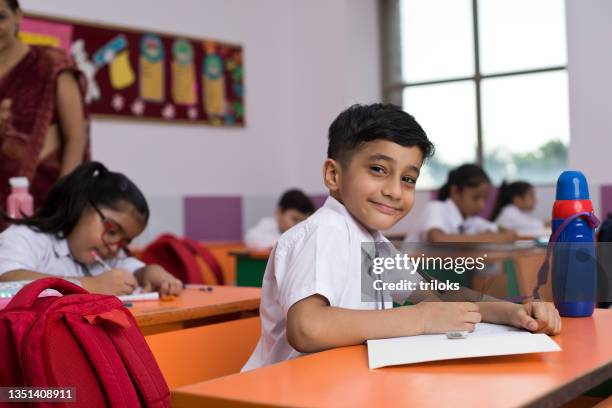 grupo de estudiantes escribiendo sobre el libro en el aula - indian child fotografías e imágenes de stock