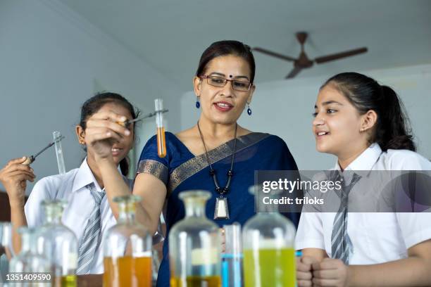 teacher doing chemical experiment with students in laboratory - india lab stockfoto's en -beelden