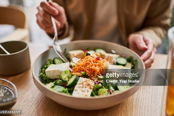 asian woman enjoying lunch at a vegan cafe. - eating vegan food stock pictures, royalty-free photos & images