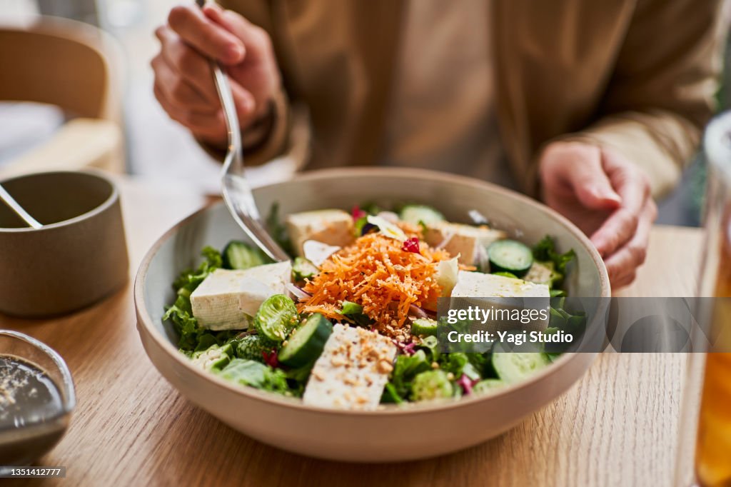Asian woman enjoying lunch at a vegan cafe.