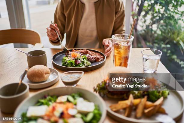 scene at a table with a couple enjoying lunch at a vegan cafe. - positive healthy middle age woman stock-fotos und bilder