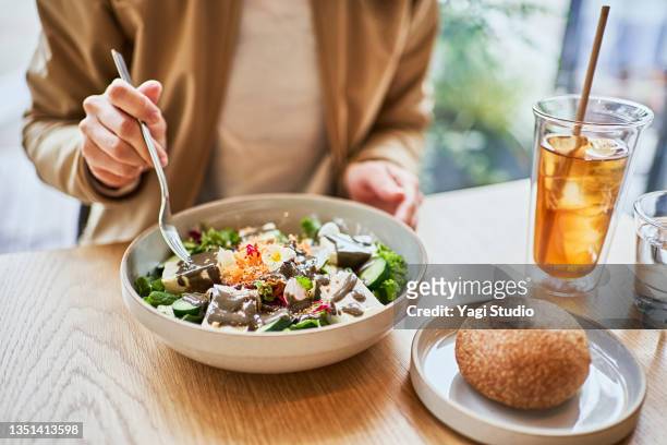 asian woman enjoying lunch at a vegan cafe. - positive healthy middle age woman stock-fotos und bilder