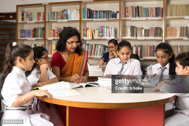 female teachers teaching students in library at school - indian school kids stockfoto's en -beelden