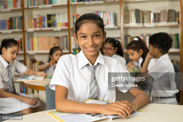 school children studying book at library - indian school kids stockfoto's en -beelden