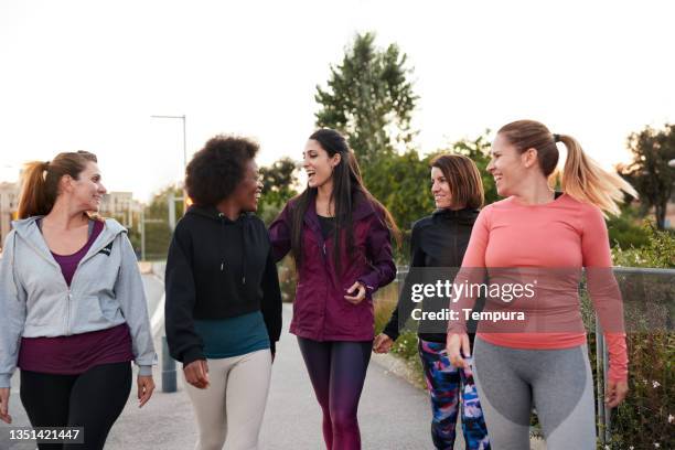 eine gruppe von frauen, die nach einer bewegung im freien spazieren gehen und sprechen. - group exercise stock-fotos und bilder