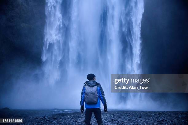 um homem com vista para a famosa cachoeira skogafoss no sul da islândia - geleira myrdalsjokull - fotografias e filmes do acervo