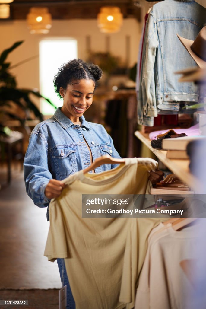 Smiling woman looking at shirt while shopping in a clothing store
