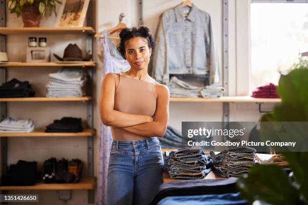 confident young female entrepreneur standing in her trendy clothing shop - portrait department store stockfoto's en -beelden