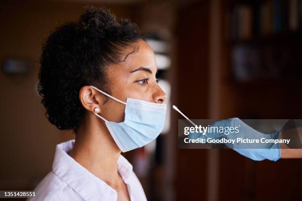 jeune femme masquée recevant un écouvillon nasal pour un test covid - coton tige photos et images de collection