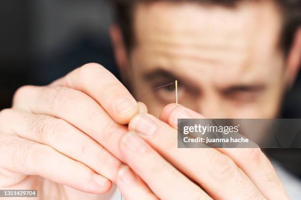 close-up view of a man threading a needle - mani fili foto e immagini stock