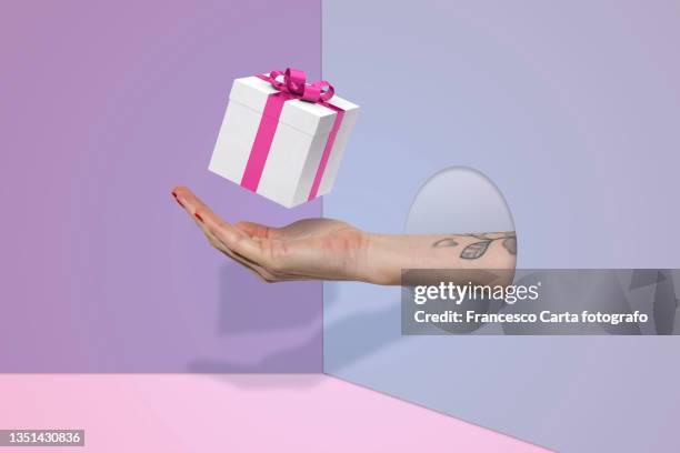 woman's hand hold a gift box on surreal background - confezione regalo foto e immagini stock