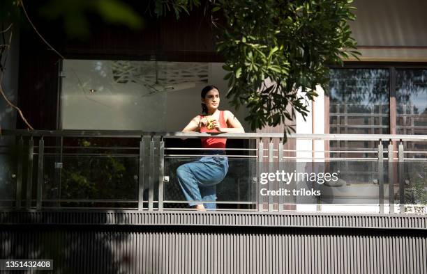 woman having coffee while admiring view from balcony - women india partition stock pictures, royalty-free photos & images