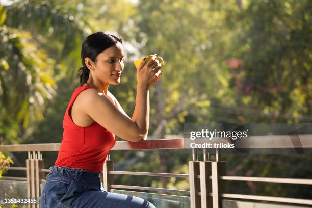 frau beim kaffee, während sie die aussicht vom balkon bewundert - tee indien trinken stock-fotos und bilder