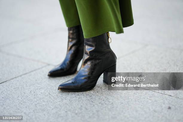 Alba Garavito Torre wears a dark green belted high waist midi skirt, black shiny leather crocodile print pattern block heels pointed ankle boots,...