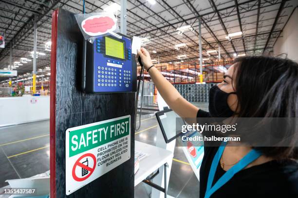 masked employee clocking in at fulfillment center - time card stock pictures, royalty-free photos & images