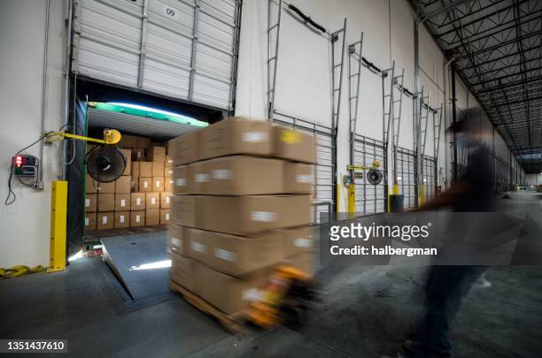 blurred view of worker unloading truck at warehouse loading dock - pallet jack stock pictures, royalty-free photos & images