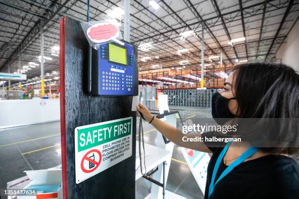 maskierte frau, die sich im fulfillment center einstempelt - stechkarte stock-fotos und bilder