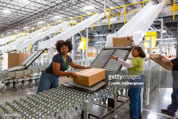 empleados del centro logístico empujan cajas a lo largo de rodillos hacia el camión - conveyer belt fotografías e imágenes de stock