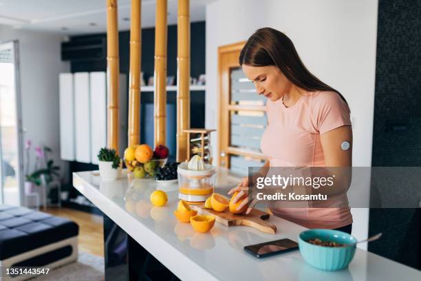 une belle jeune femme enceinte coupe des oranges et des citrons dans la cuisine pour faire du jus pressé - diabète photos et images de collection