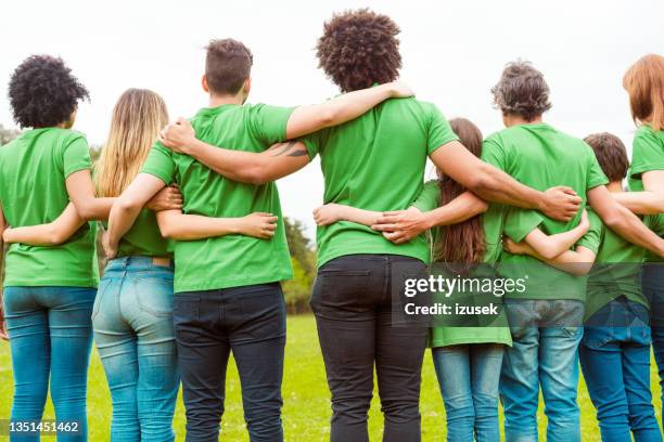 male and female volunteers together at park - green tee stock pictures, royalty-free photos & images