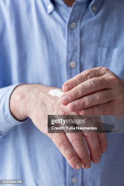 senior man smears his hands with cream, close-up - trockene haut stock-fotos und bilder