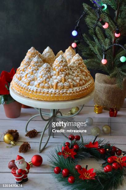 image of homemade, christmas tree shaped, lemon drizzle bundt cake on white, marble and metal cake stand surrounded by christmas decorations, santa claus, lemon flavoured ring sponge covered with dusting of icing sugar, black background - baking dish stock pictures, royalty-free photos & images