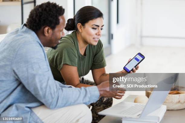 soldatin und ihr mann überprüfen hausfinanzen - african lady sitting and looking at her smartphone stock-fotos und bilder