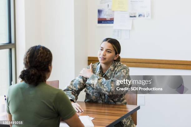 female soldier talks with doctor about shoulder pain - injured soldier imagens e fotografias de stock