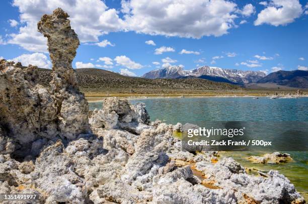 scenic view of rocks by lake against sky - sedimentary stockfoto's en -beelden