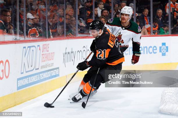 Scott Laughton of the Philadelphia Flyers clears the puck past Lawson Crouse of the Arizona Coyotes at Wells Fargo Center on November 02, 2021 in...