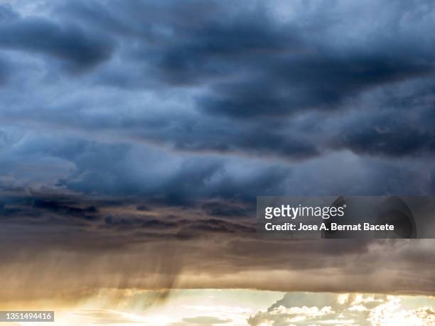 full frame of storm clouds and rain in the sky during a sunset. - grey clouds stock pictures, royalty-free photos & images