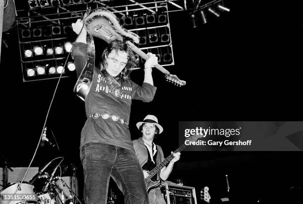 American Blues and Rock musician Stevie Ray Vaughan plays guitar over his head as he performs onstage, with his band Double Trouble, during the...