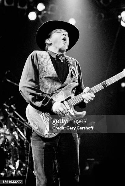 American Blues and Rock musician Stevie Ray Vaughan plays guitar as he performs onstage, with his band Double Trouble, during 'The Fire Meets the...