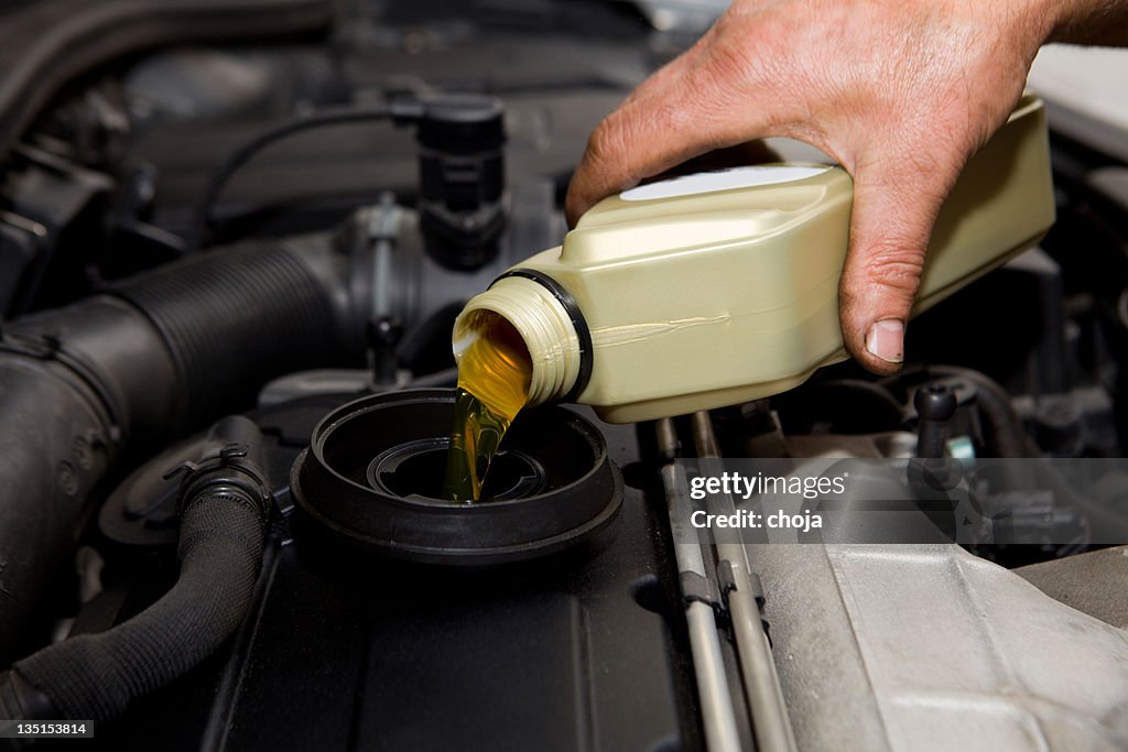 In auto repair shop...Car mechanic is changing engine oil