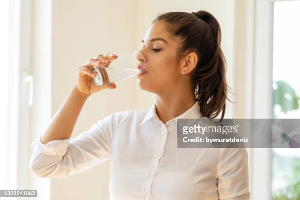junge frau trinkt ein glas wasser - drinking water glass woman stock-fotos und bilder