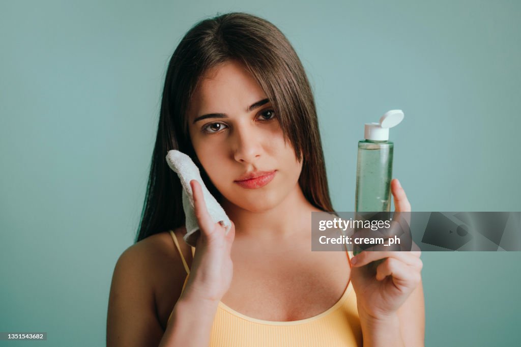Frau, die make-up mit mizellaren Wasser und einem wiederverwendbaren Wattepad ausziehen