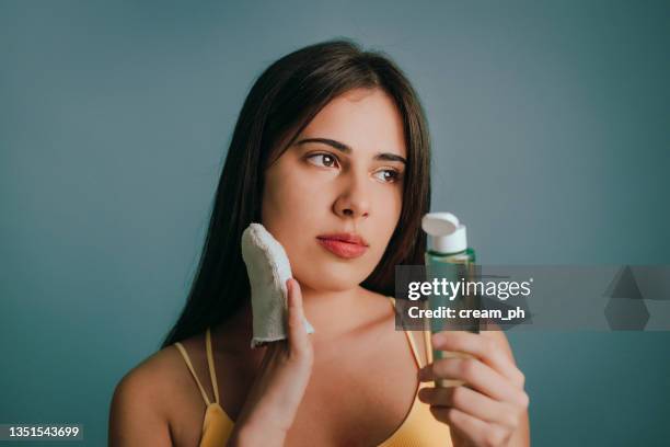 woman taking off make-up with micellar water and a reusable cotton pad - peeling off bildbanksfoton och bilder