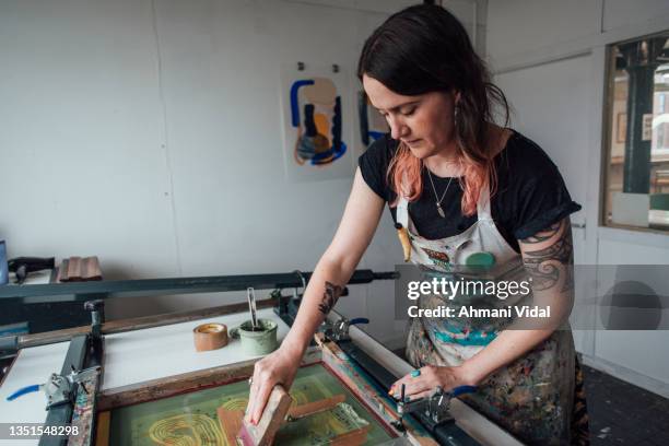 artist and printmaker working a printing press - silk screen stock pictures, royalty-free photos & images