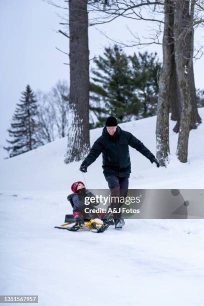 family tobogganing during winter. - ski holiday stock pictures, royalty-free photos & images