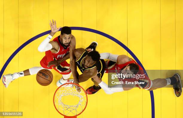 Garrett Temple of the New Orleans Pelicans puts up a shot while Andrew Wiggins of the Golden State Warriors and Jonas Valanciunas of the New Orleans...