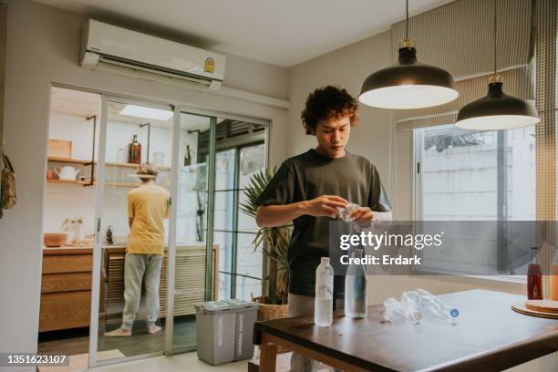 after drinking water, gay man organizes plastic bottles to recycling bin-stock photo - reusable energy stock pictures, royalty-free photos & images