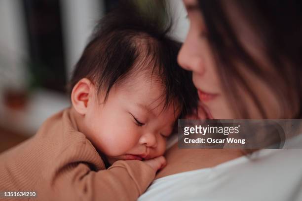 close-up of cute asian baby girl sleeping peacefully in the arms of her mother - 若い カワイイ 女の子 日本人 ストックフォトと画像