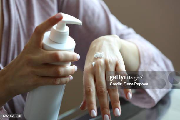 young adult woman using hand lotion at home - hand eczema stock pictures, royalty-free photos & images