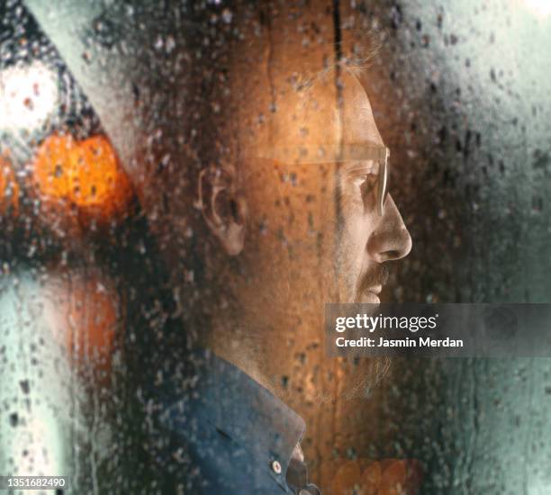 portrait of man on rain night window - water cooler stock-fotos und bilder