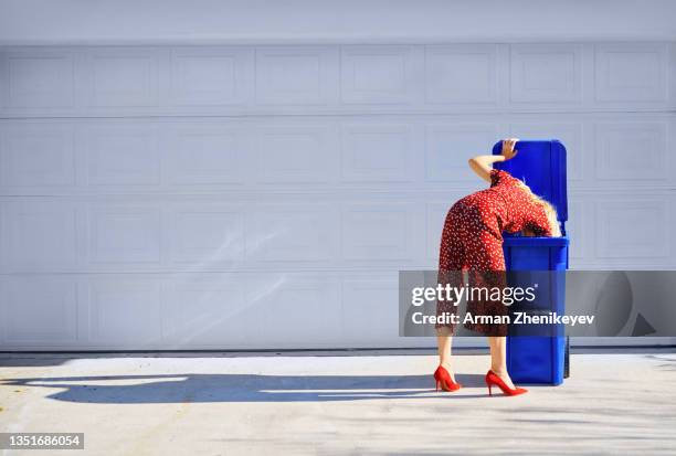 fashionable woman wearing vinous jumpsuit while diving inside the garbage can - hiding rubbish stock pictures, royalty-free photos & images